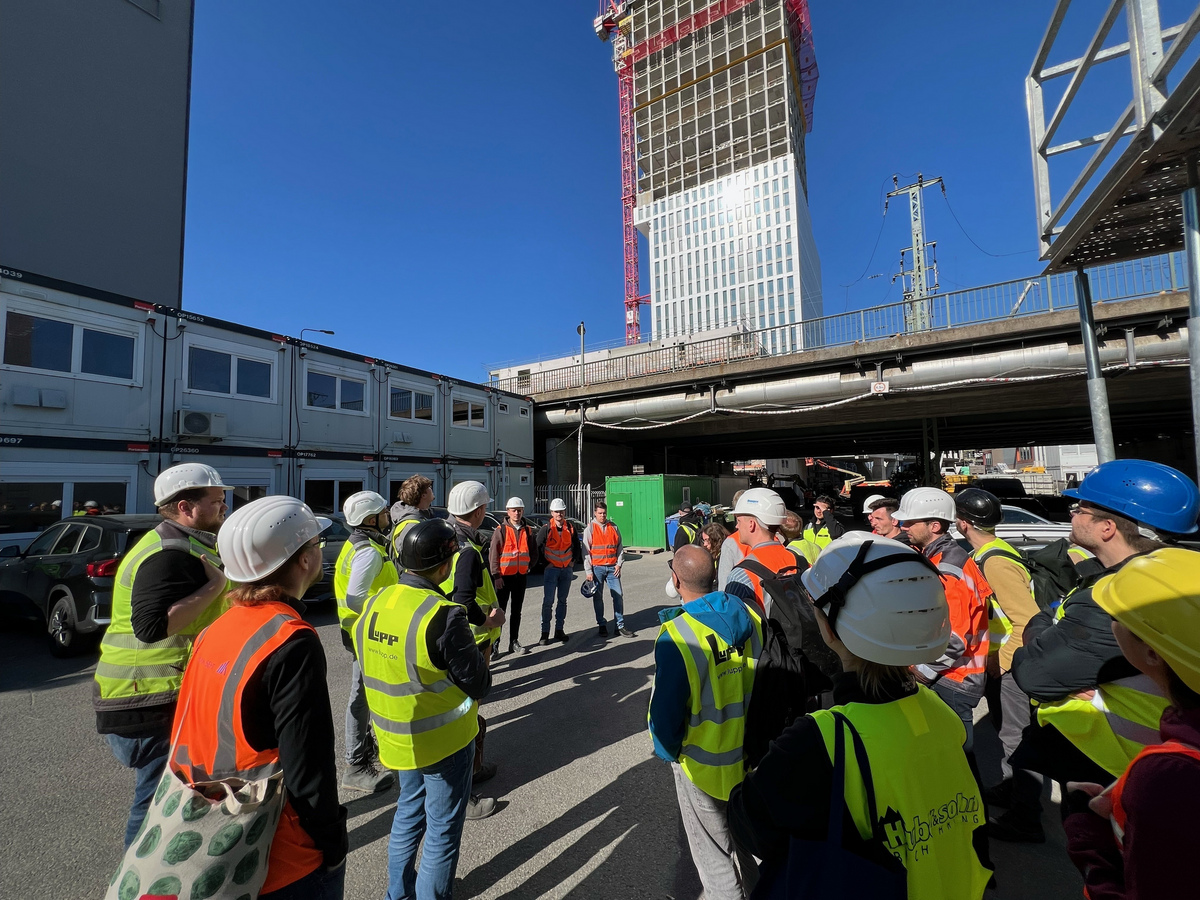 Gruppe von Menschen mit Warnwesten und Bauhelmen auf Hochhausbaustelle