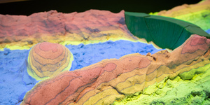 Sandkasten für Forschungszwecke: Mit der „Augmented Reality Sandbox“ lassen sich Landschaften aus Sand modellieren. Wasserwirtschaftsexperte Jochen Hack arbeitet mit digitalen Landschafts- und numerischen Simulationsmodellen, hier bildet die Sandbox eine Brücke zwischen Virtualität und Haptik. Foto: h_da / Markus Schmidt. 
