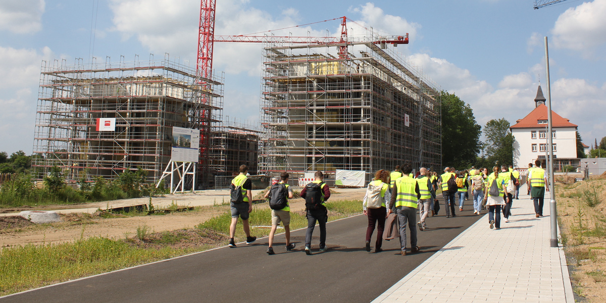 Gruppe des Fachbereichs läuft über Baustelle Ludwigshöhviertel mit Baukränen und Rohbauten 