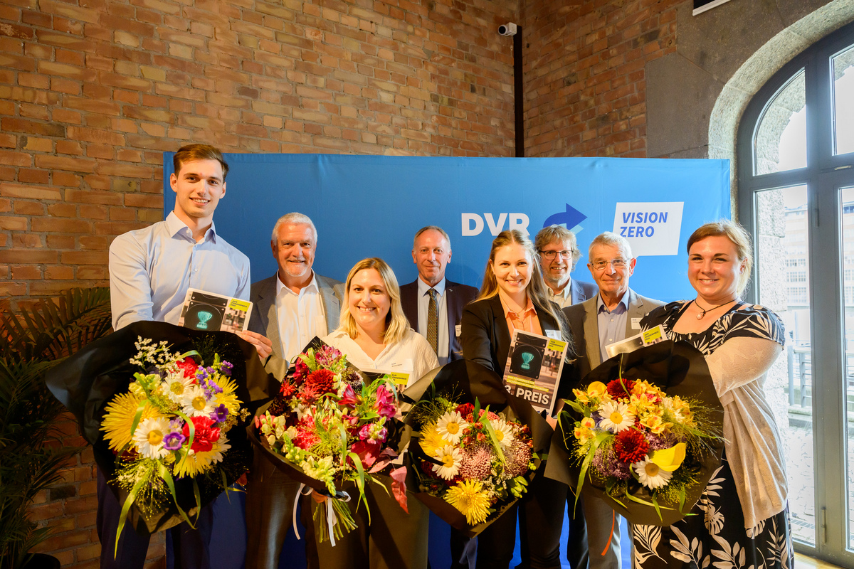 Gewinnerinnen und Gewinner des DVR Förderpreises 2025 mit Blumen vor DVR Stellwand
